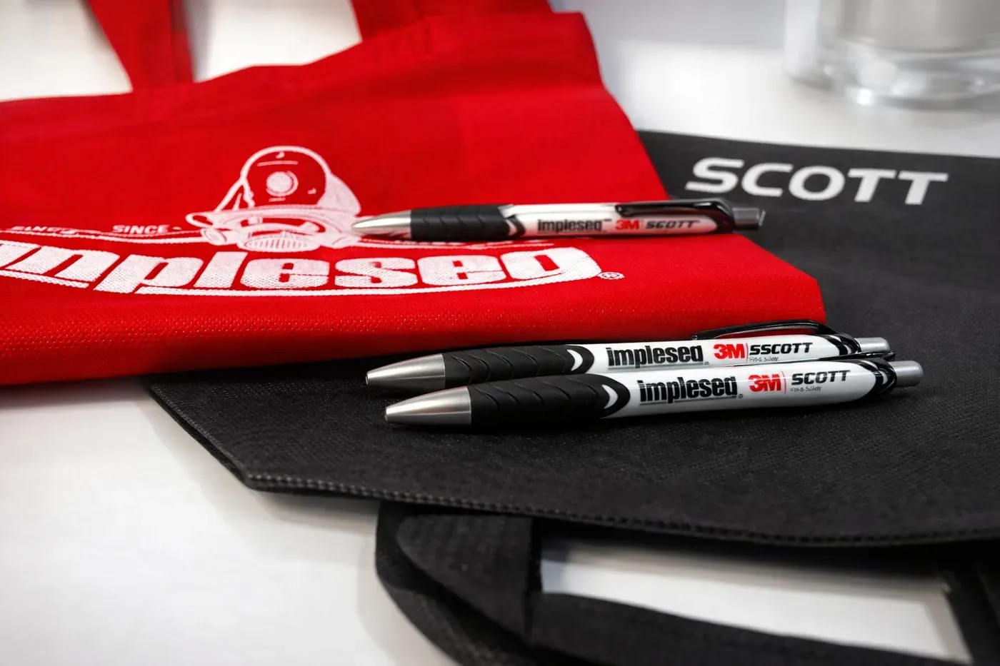 Bolsas ecológicas rojas y negras con lapiceros marcados con logo de empresa